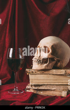 Crâne halloween sur les livres anciens avec verre sur tissu rouge Banque D'Images
