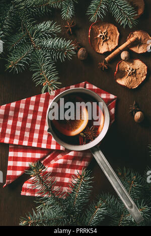 Vue de dessus du vin épicé chaud traditionnel de Noël sur fond de bois avec des tranches de pommes séchées et des branches de pins Banque D'Images