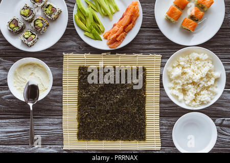 Vue de dessus de nori et de délicieux ingrédients pour la cuisson sushi on wooden table Banque D'Images