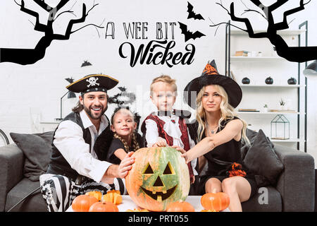 Portrait de famille dans divers costumes de Halloween à table de café avec des citrouilles à la maison avec "un tout petit peu méchant lettrage' Banque D'Images