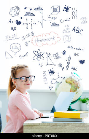 Belle lycéenne aux cheveux rouges dans eyeglasses smiling at camera while l'étude avec des livres et l'ordinateur portable, avec des devoirs et des icônes Banque D'Images