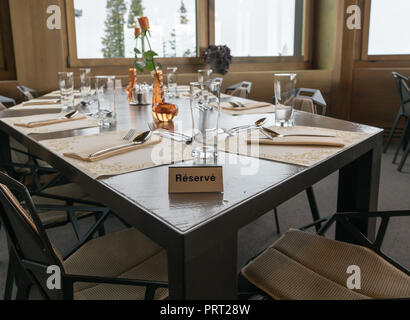 Table de restaurant avec d'élégants couverts et des fleurs et un signe réservé écrit en français Banque D'Images