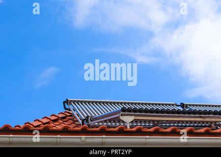 Capteurs solaires pour eau chaude et chauffage sur le toit de maison sur fond de ciel bleu Banque D'Images