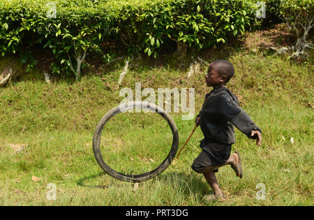 Un garçon rwandais jouant avec une roue de bicyclette en milieu rural au Rwanda. Banque D'Images