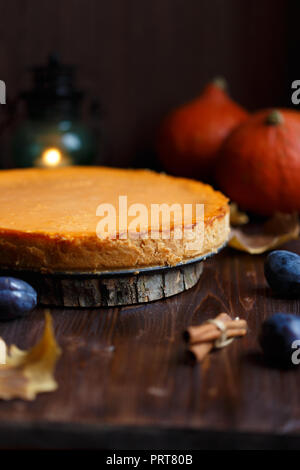 Gâteau au fromage à la citrouille cuite, à la maison, de citrouilles, de prune, de vanille , feuillage sur un tableau noir en bois. Banque D'Images