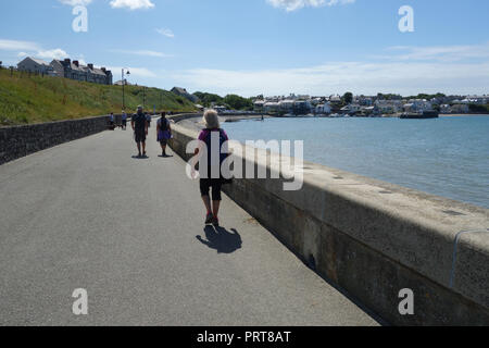 Un homme et deux femmes randonneurs marche sur l'île d'Anglesey Coastal Path dans le village de pêcheurs de Cemaes, Pays de Galles, Royaume-Uni. Banque D'Images