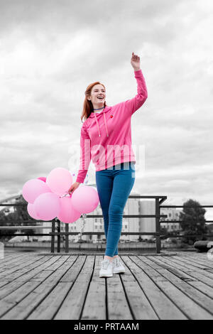 Smiling girl debout sur la jetée et holding ballons roses Banque D'Images