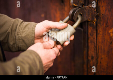 Les mains de l'homme fermer la serrure, déverrouiller un cadenas anciens Banque D'Images