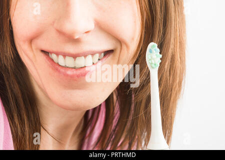 Vue rapprochée de la santé des dents blanches de femmes avec brosse à dents électrique, selective focus Banque D'Images