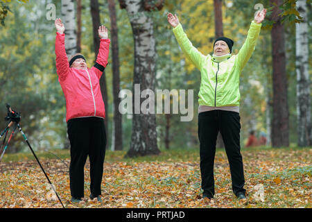A mature woman performing warm-up dans un parc d'automne après une marche scandinave Banque D'Images