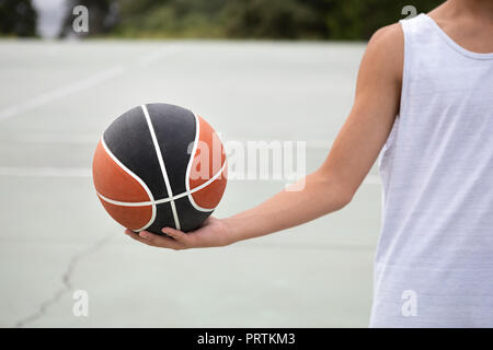 Les adolescents de sexe masculin de basket-ball player holding ball le basket-ball, cropped Banque D'Images
