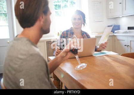 Table de cuisine à couple drinking red wine alors que doing paperwork Banque D'Images