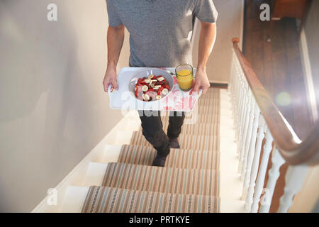 Jeune homme exerçant son plateau de petit-déjeuner à l'étage, du cou vers le bas Banque D'Images