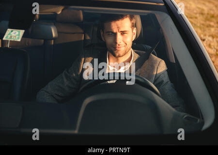 Vue avant du smiling bussinesman litigieux au volant de sa voiture Banque D'Images