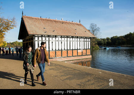 Un jeune couple en train de marcher au-delà de la remise à bateaux près de la Serpentine dans Hyde Park, Royaume-Uni Banque D'Images