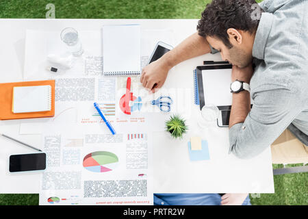 Les jeunes hommes d'dormir sur la table et tapis d'herbe verte à l'équipe d'affaires, bureau moderne Banque D'Images