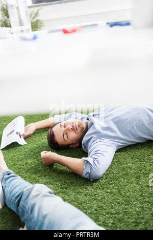 Les jeunes hommes d'dormir sur le tapis d'herbe verte à l'équipe d'affaires, bureau moderne Banque D'Images