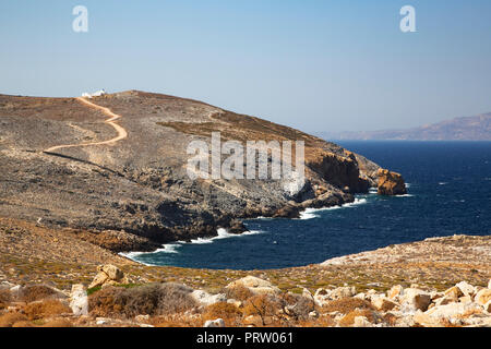La côte rocheuse de Sifnos avec l'église d'Agios Georgios de Heronissos dans la distance. Banque D'Images