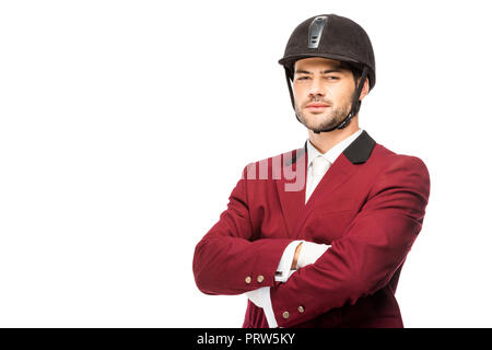 Beau jeune cavalier en uniforme et casque looking at camera with crossed arms isolated on white Banque D'Images