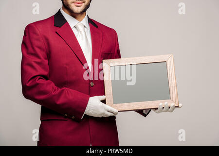 Cropped shot du jeune cavalier en uniforme holding blank chalkboard isolé sur gray Banque D'Images
