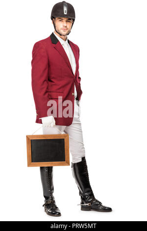 Jolie jeune cavalier en uniforme holding blank chalkboard and looking at camera isolated on white Banque D'Images