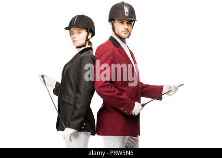 Les jeunes cavaliers en uniforme et casques holding horseman sticks tout en se penchant en arrière à l'arrière et looking at camera isolated on white Banque D'Images
