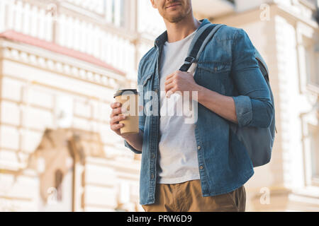 Cropped shot of young man with coffee pour aller marcher sur sac à dos street Banque D'Images