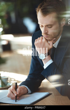 L'accent businessman doing paperwork à table avec tasse de café dans le Banque D'Images