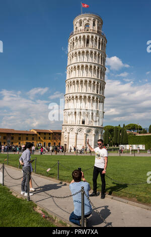 Tourist qui pose pour photo contre la tour penchée de Pise, Toscane, Italie Banque D'Images