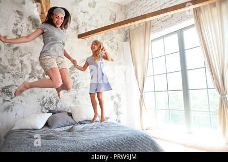 Heureux jeune femme et sa petite fille mignonne s'amusent dans le lit tout en étant à la maison ensemble. Happy Mother's Day Banque D'Images