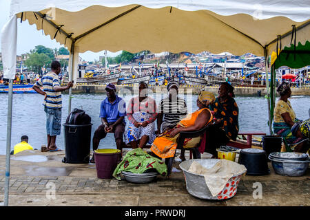 SEKONDI TAKORADI, GHANA - 10 avril 2018 : Les femmes en robe colorée attendent avec leurs seaux d'étain pour les poissons d'être débarqué à occupé Bosomtwi Pêche Sam Harbou Banque D'Images