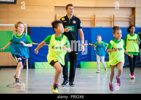 05 octobre 2018, Berlin : Christian Prokop (M), entraîneur de handball nationale, mène un programme de formation avec des élèves de l'école primaire Am Faulen Voir. L'école primaire de Berlin avait gagné un cours de formation de handball avec l'entraîneur national Prokop dans un projet d'école nationale de la Fédération allemande de Handball (DHB) et l'AOK. Avec ce projet, les deux partenaires veulent motiver les enfants pour plus d'exercice et de handball. Photo : Arne Immanuel Bänsch/dpa Banque D'Images