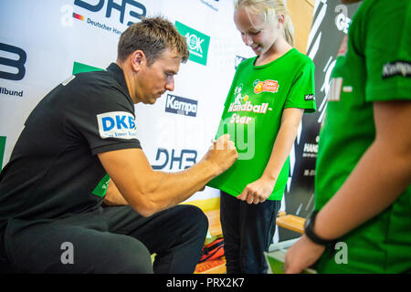 05 octobre 2018, Berlin : Christian Prokop (l), entraîneur de handball nationale, signe un T-shirt de l'étudiant Pia (r) après une formation de handball à l'école primaire Am Faulen Voir. L'école primaire de Berlin avait gagné un cours de formation de handball avec l'entraîneur national Prokop dans un projet d'école nationale de la Fédération allemande de Handball (DHB) et l'AOK. Avec ce projet, les deux partenaires veulent motiver les enfants pour plus d'exercice et de handball. Photo : Arne Immanuel Bänsch/dpa Banque D'Images