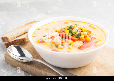 La soupe avec la crème, le maïs, les haricots, les poivrons et l'oignon avec du pain grillé sur planche de bois Banque D'Images