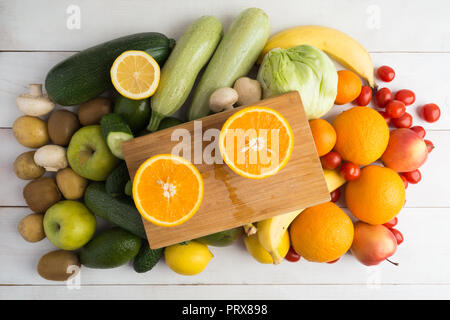 Partie deux d'orange par dessus bord et autres fruits et légumes sur fond de bois blanc Banque D'Images