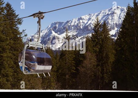 Garmisch-Partenkirchen, Allemagne - 7 avril 2018 - cabine d'un ascenseur de ski avec des skieurs ; forêts et de magnifiques couverts de neige Alpes en arrière-plan Banque D'Images