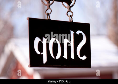 Profondeur de champ étroit sur la boutique sign hanging from metalworking shop. Le métal rouillé signe a ses lettres découpées et se bloque à partir de bagues soudées. Et leur servent Banque D'Images