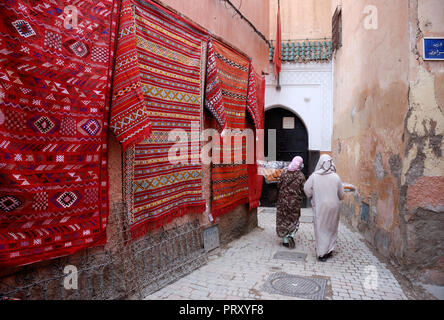 Marrakech,MAROC-MARS 05, 2009 : tapis marocain le long d'une petite ruelle dans le souk avec deux femmes avec de la nourriture à la fin de la rue Banque D'Images