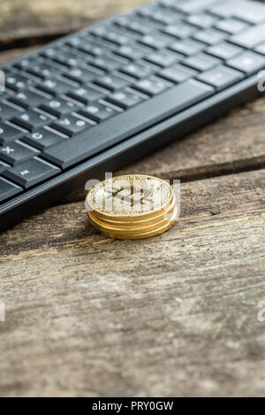 Pile de pièces de monnaie Bitcoin or près de black clavier du PC en gros plan sur table en bois avec copyspace. Banque D'Images