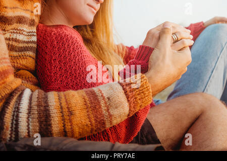 L'homme et de la femme tenant leurs mains ensemble, ils portent des anneaux de mariage et hugg à sunrise. Qu'§s comment un couple marié heureux ressemble. Banque D'Images