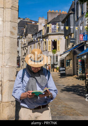 GUIDE TOURISTIQUE EXPLOREZ LE quartier de LA vieille VILLE DE FRANCE avec un touriste portant un chapeau de soleil lisant un guide touristique de Bretagne Michelin Quimper Bretagne Banque D'Images