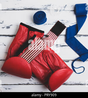 Paire de gants de boxe en cuir bleu, rouge bandage et silicone bouche cap sur un fond de bois blanc Banque D'Images