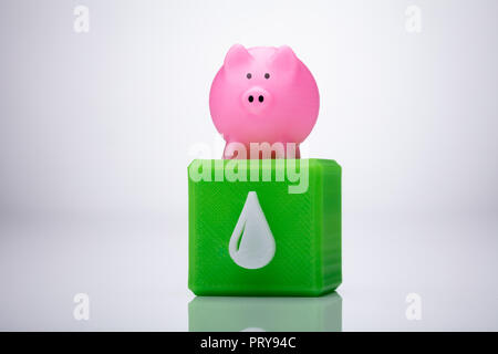 Close-up of a Pink Piggybank sur m3 avec bloc Waterdrop Icône sur fond réfléchissant Banque D'Images