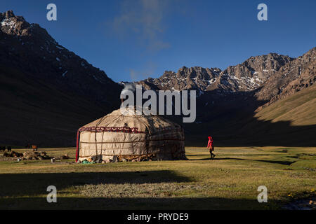 Jeune fille près de la yourte kirghize au lever du soleil, heure d'or dans la vallée de l'Pshart à distance dans les montagnes du Pamir, région autonome du Haut-Badakhchan, Tadjikistan. Banque D'Images