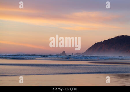 Plage au coucher du soleil du Pacifique avec des montagnes et des roches à l'horizon. Banque D'Images