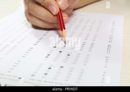 L'homme est libre de remplir la fiche de lecture OMR avec crayon en main. isolé sur fond blanc. Banque D'Images