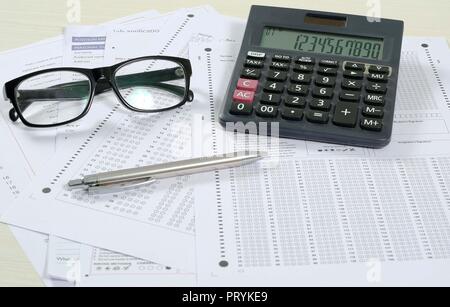 Photo de plusieurs feuilles omr, un stylo, lunettes et Calculatrice. Isolé sur fond blanc. Banque D'Images