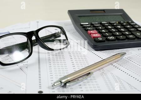 Photo de l'examen de plusieurs feuilles, omr stylo, lunettes et Calculatrice. Isolé sur fond blanc. Banque D'Images