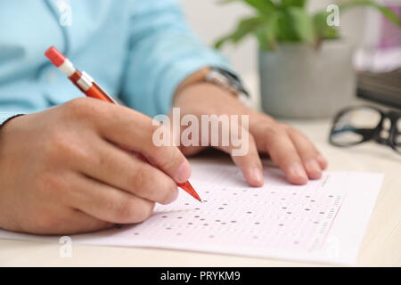 L'homme est de remplir la fiche de lecture OMR avec stylo. Banque D'Images