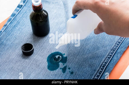 Les jeans sont tachés dans Zelenka. Pour nettoyer les vêtements. Égouttez le peroxyde d'hydrogène sur une tache. Banque D'Images